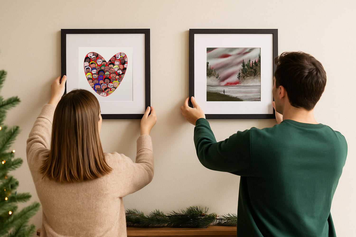 Two people hanging framed pictures on a wall
